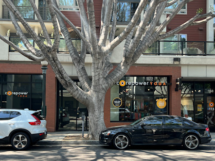 Red brick building with large square windows and a black CorePower yoga sign centered above