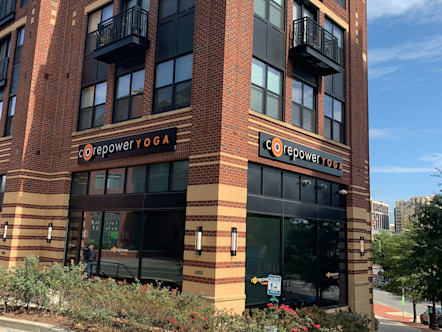 CorePower Yoga sign touted on a beautiful three-story brick building with tan accents and green flowers framing the sides