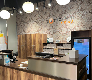 Blackhawk CorePower studio with a wooden front desk and a unique damask wallpaper in neutral colors