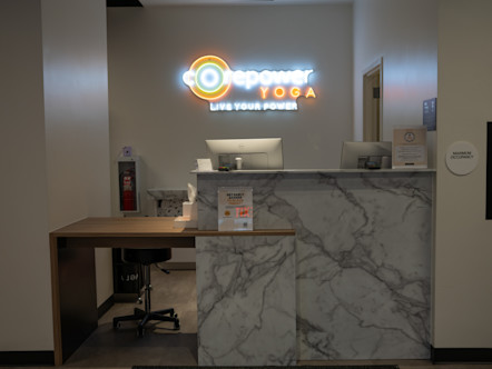 Reception desk with marble front at the East Village CorePower Yoga studio featuring illuminated neon sign reading "CorePower YOGA - LIVE YOUR POWER"