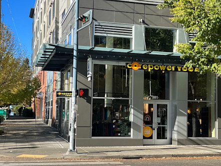 CorePower Yoga sign above windowed entryway of a light grey building with a dark green awning over top 