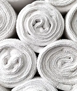 Stack of rolled white towels arranged in a pyramid, close-up view