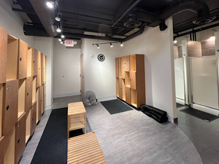 CPY locker room with grey colored flooring and black runner rugs with 3 levels of wooden lockers on either wall