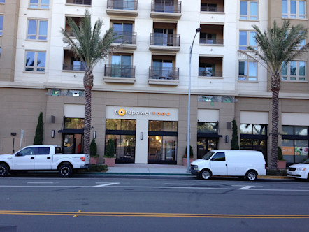 CorePower Yoga Golden Triangle studio's logo displayed on a tan building with palm trees lining the sidewalk