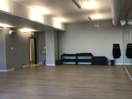 Studio room with light tan walls and light brown floors 