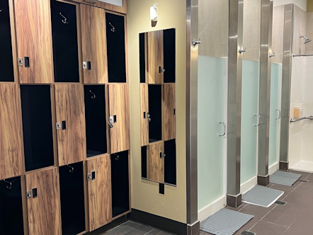Mission Viejo locker room area with wooden lockers alternated with black cubbies and three showers with frosted glass doors