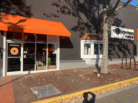 Dark gray building touting bright orange awnings over a white door with a CorePower symbol graphic