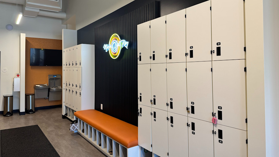 The locker hallway inside the studio, a run of lockers with a bench and the studio's neon logo