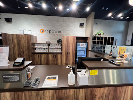 Tiered wooden and metal front desk area in front of a white patterned wall with a CPY sign centered above 
