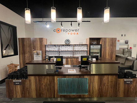 CPY Torrance studio entrance with a metal and wooden tiered front desk and black CorePower yoga mats lining either side