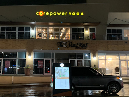 Yellow CorePower Yoga sign with a brown wooden awning underneath on the second level of a tan brick exterior shopping center
