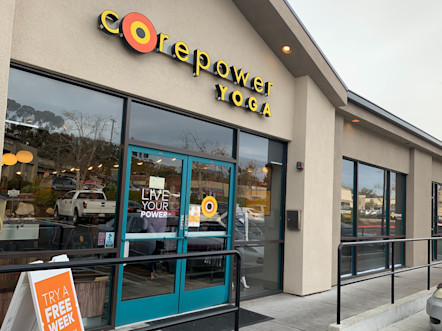 CorePower Yoga sign touted on a traditional tan building with teal double-doors and big glass windows
