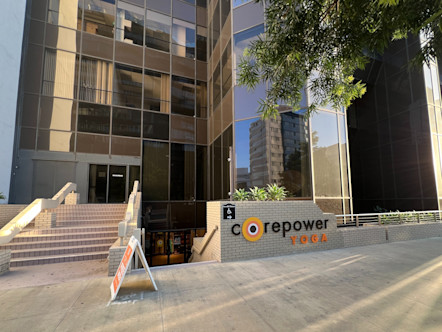 Large building with a tan brick sign with a black CPY sign with a staircase to the right leading down to glass double doors of a CPY studio