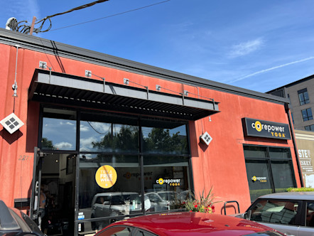 CorePower Yoga sign on a black background above large windows on a red stucco building 