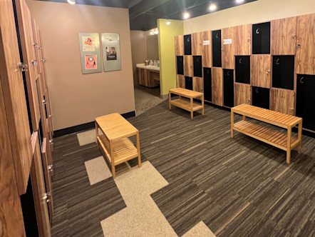 Mission Valley locker room with tan lockers, black cubbies, neutral colored walls, and grey and tan patterned carpet floors