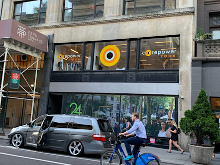 Bryant Park exterior with three windows, each displaying either the CPY sign or logo above a retail space on a light tan concrete building 