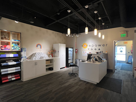 Sherman Oaks CPY studio's front desk area with white cabinetry in front of a large while marble desk with cream wallpaper on the walls surrounding