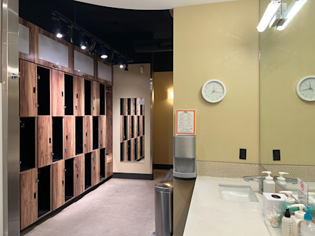CorePower Yoga locker room with wooden lockers on one side and a white marble vanity with a large mirror above on the other side