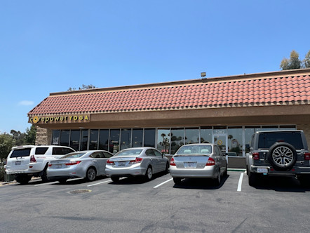La Mesa CorePower Yoga studio in a one story, Spanish-style red roof tiled building with a yellow CPY logo to the left and windowed exterior below
