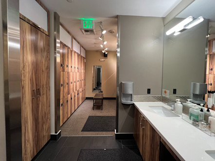 Locker room area with wooden lockers and large wooden doors; sink and mirror area directly adjacent
