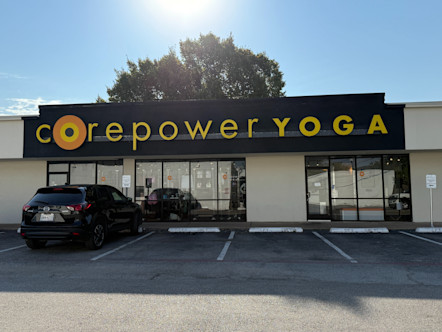 Tan stucco building with a large black panel showcasing a large, yellow CorePower Yoga sign