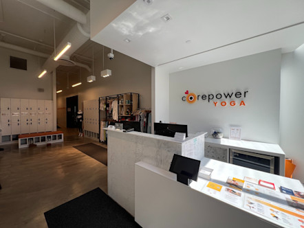 Front desk area with a large dual level marble desk in front of a white wall with a CorePower Yoga Sign on it