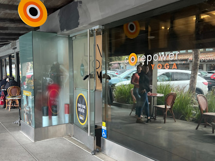 Gray concrete building with modern sleek glass doors touting the CorePower Yoga logo and sign
