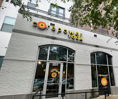 CorePower Austin Triangle studio's exterior white brick wall with the orange logo touted above glass doors