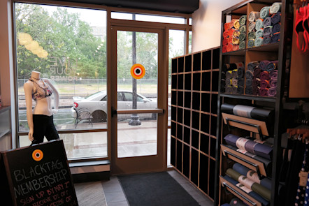 Wooden shoe bins displayed next to colorful yoga mats and towels