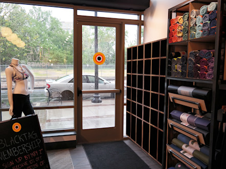 Wooden shoe bins displayed next to colorful yoga mats and towels