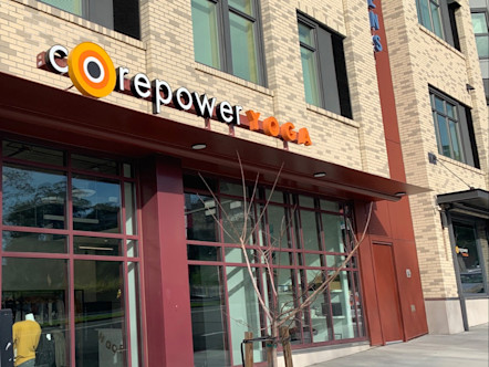 CorePower Yoga light tan brick storefront with signage above windows with dark red trim