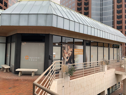 Wilshire studio on the second story of a shopping center with light grey window shades and a red brick walkway surrounding