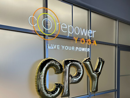 CPY balloon letters in front of a frosted glass panel door and under a CorePower Yoga neon sign 