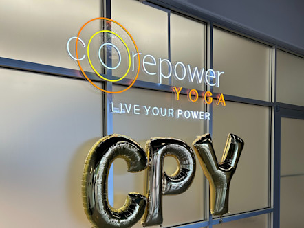 CPY balloon letters in front of a frosted glass panel door and under a CorePower Yoga neon sign