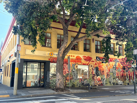 Duboce exterior with the CorePower sign above a glass door entryway on a yellow and muraled corner building
