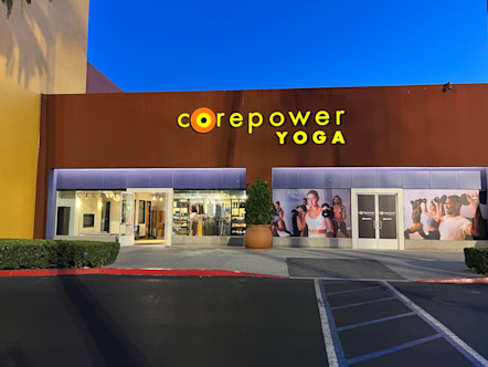 Orange stucco exterior wall touting a bright yellow CorePower Yoga sign