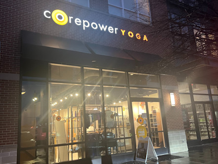 CorePower Yoga sign touted on a brick and stone building with large floor to ceiling windows and a black awning