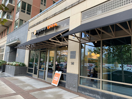 CorePower Yoga sign touted on the exterior of a tan building with dark dray metallic awnings