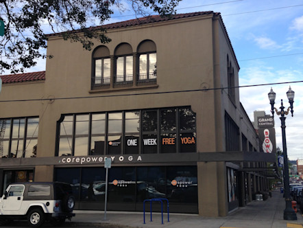 Tan stucco Spanish-style building with red shingles and large windowed area with a black awning and a white CPY sign on it