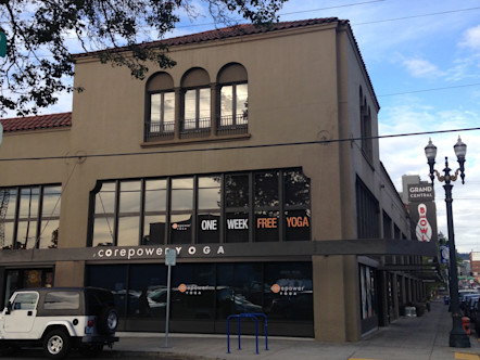 Tan stucco Spanish-style building with red shingles and large windowed area with a black awning and a white CPY sign on it