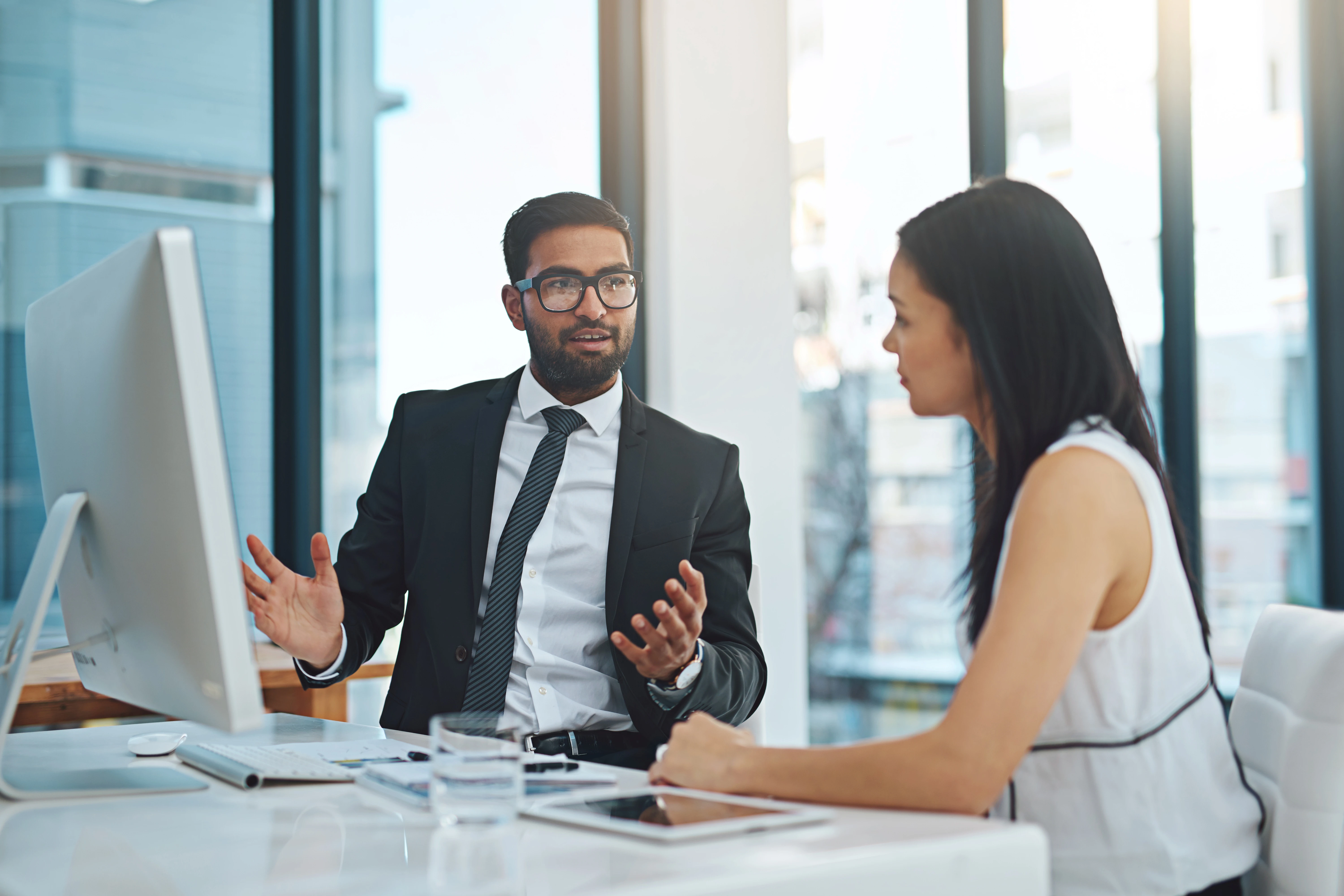 Two co-workers conferring at table with computer