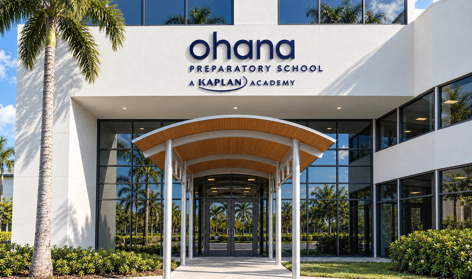 Exterior of Ohana Preparatory School, a Kaplan Academy, featuring a modern white building with a wood-canopied entrance and palm trees.
