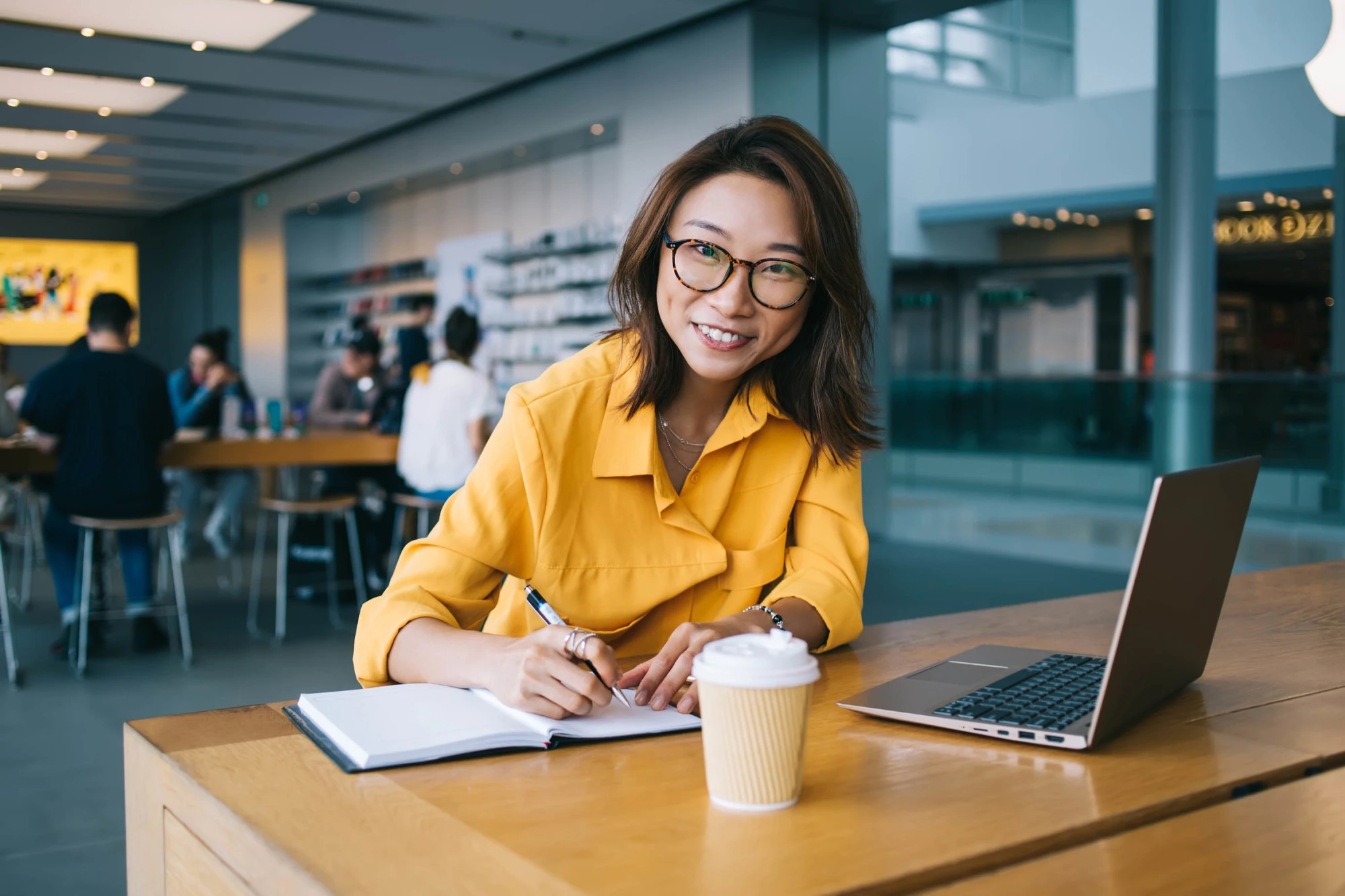 woman in orange shirt writing in notebook