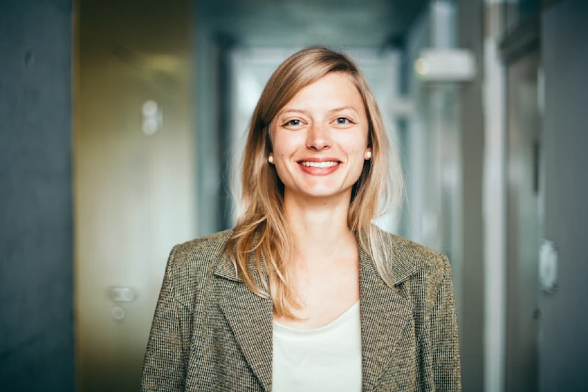 Female professional standing in a hallway smiling