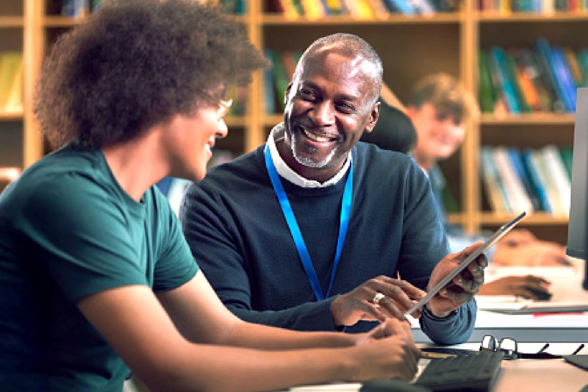 Teacher working with student in library, both smiling
