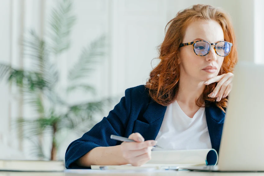 Woman with glasses working on laptop