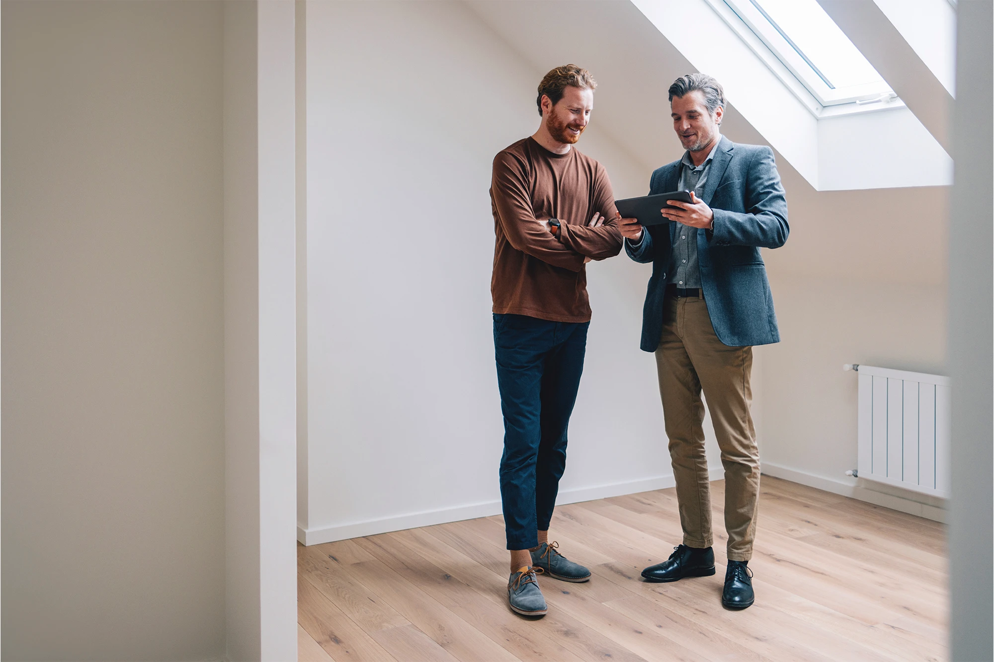 Two male real estate professionals engaged in a discussion during an open house, standing inside a modern property.