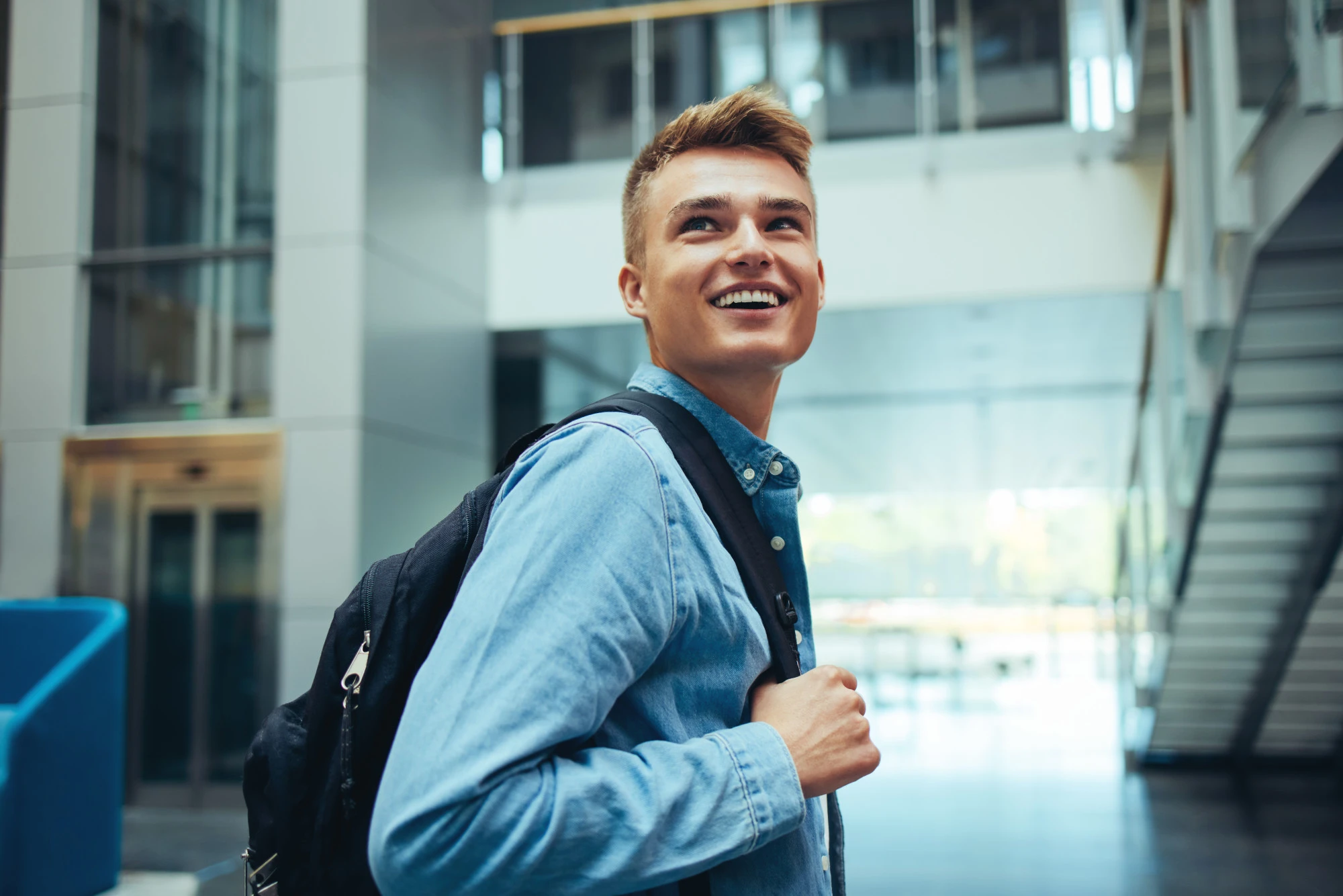 A smiling male student with a backpack looking over his shoulder