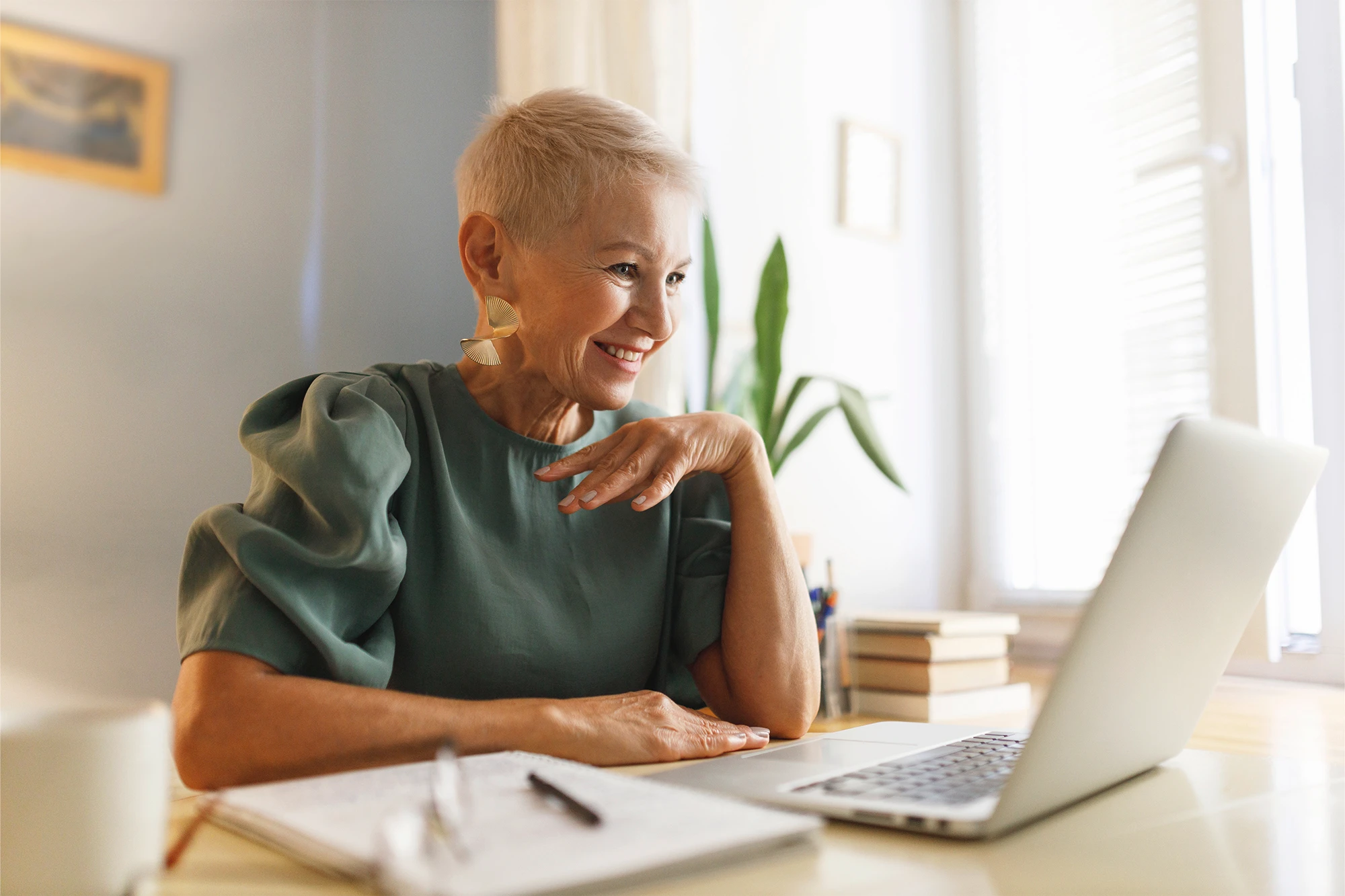 Real estate professor seated at a table with a laptop, conducting an online meeting.