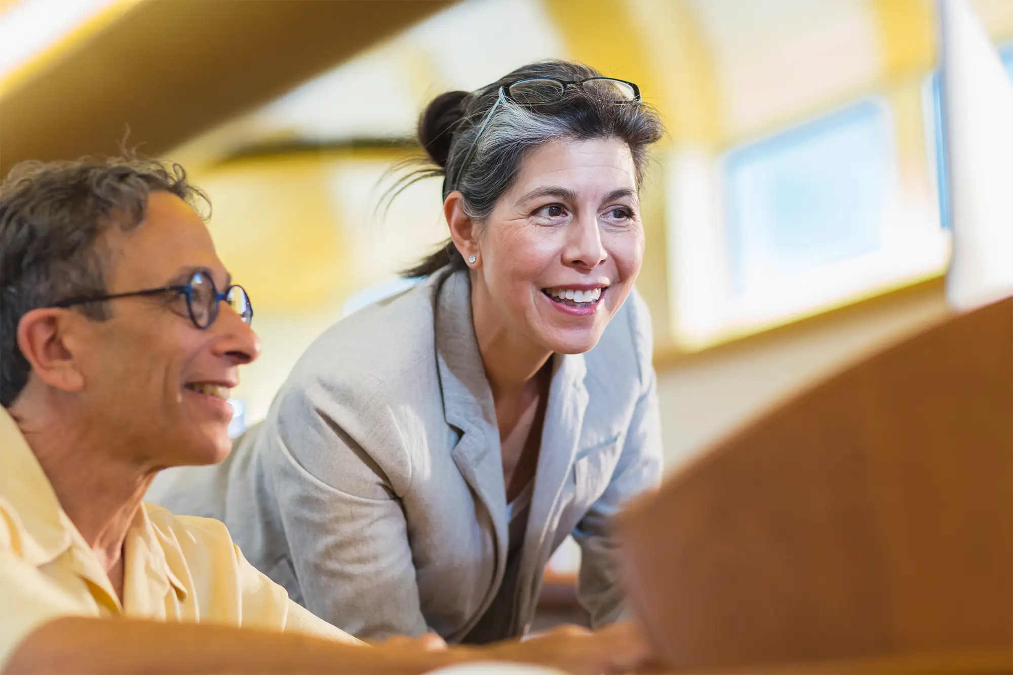 Real estate professionals reviewing documents together, seated at a table with a laptop, engaged in a discussion.